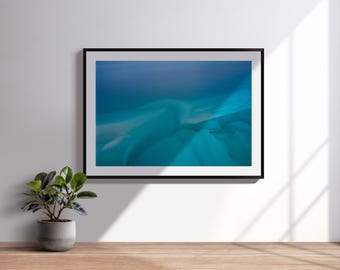 Könnte beinhalten: Gerahmter abstrakter Kunstdruck mit einer Mischung aus Blau- und Türkistönen, die ein Gefühl von Tiefe und Bewegung erzeugt. Das Kunstwerk wird an einer weißen Wand ausgestellt, mit einer kleinen Topfpflanze im Vordergrund.