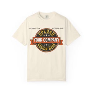 May include: Off-white t-shirt with a circular logo design. The logo reads "UPLOAD YOUR COMPANY DESIGN HERE" in a vintage style, with orange and black accents. The shirt has a crew neck and short sleeves.