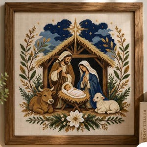 Puede incluir: Un bordado en punto de cruz enmarcado que representa una escena de natividad con una estrella central, un establo, figuras, un bebé en un pesebre, una vaca y un cordero. El diseño está enmarcado por follaje verde sobre un cielo nocturno azul.