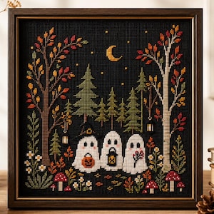 May include: A framed cross-stitch embroidery featuring three white ghosts in a dark forest at night. The scene includes autumn trees with orange and red leaves, green pine trees, small red mushrooms, a yellow crescent moon, and stars. The ghosts hold a jack-o'-lantern, a lantern, and a sprig of berries.
