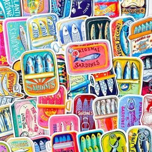 May include: A collection of colorful sardine can stickers with various designs. The stickers feature illustrations of sardines, text like "Original Sardines," and other branding elements. The color palette includes blues, pinks, yellows, and greens.