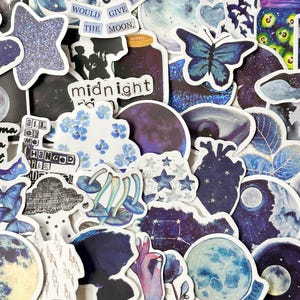 May include: A collection of assorted stickers featuring celestial, floral, and nature-themed designs in shades of blue, purple, and black. Visible text includes "I WOULD GIVE THE MOON," "midnight," and "all of me changed like midnight."