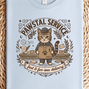 Peut inclure: T-shirt bleu clair avec un chat de dessin animé en uniforme de facteur, tenant un colis. Le motif comprend le texte "PAWSTAL SERVICE" et "fast & fur-ious delivery", ainsi que des illustrations sur le thème postal.