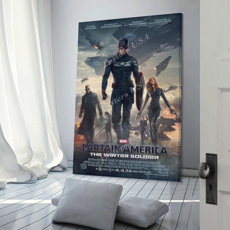 Puede incluir: Un p&oacute;ster enmarcado de la pel&iacute;cula "Capit&aacute;n Am&eacute;rica: El Soldado de Invierno". El p&oacute;ster presenta al Capit&aacute;n Am&eacute;rica, Viuda Negra y otros personajes. El t&iacute;tulo y los cr&eacute;ditos de la pel&iacute;cula se muestran en la parte inferior, con la bandera de EE. UU. de fondo.