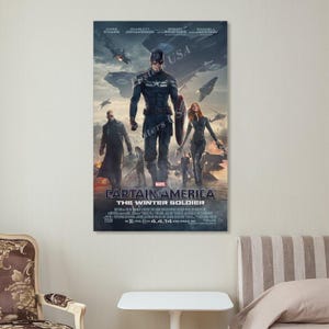 Puede incluir: Un p&oacute;ster enmarcado de la pel&iacute;cula "Capit&aacute;n Am&eacute;rica: El Soldado de Invierno". El p&oacute;ster presenta al Capit&aacute;n Am&eacute;rica, Viuda Negra y otros personajes. El fondo muestra un paisaje urbano futurista con aviones. El t&iacute;tulo y los cr&eacute;ditos se muestran en la parte inferior.