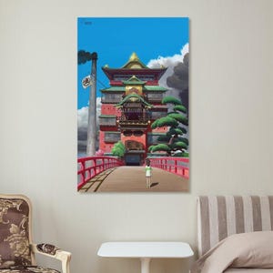 May include: A framed print of a scene from the animated film Spirited Away. The image features a red building with a bridge, a character walking, and the text "GAMING COLLECTIBLES". The sky is blue with clouds.