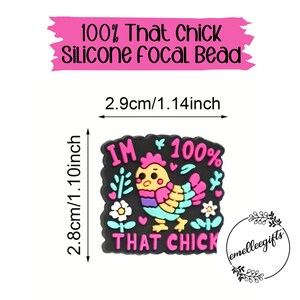 May include: A black silicone focal bead with a colorful cartoon chicken design. The bead is 1.14 inches wide and 1.10 inches tall, with the text "I'M 100% THAT CHICK". The text "100% That Chick Silicone Focal Bead" is above the bead.