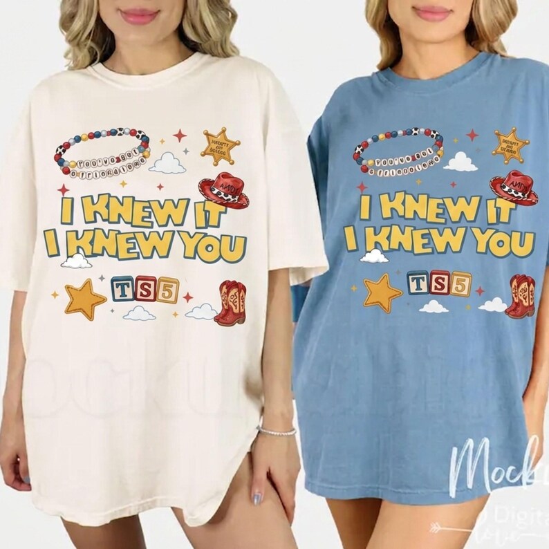 May include: Two short-sleeve t-shirts, one cream and one blue, featuring a graphic print with the text "I KNEW IT I KNEW YOU" and "TS5". The design includes a beaded bracelet, a sheriff badge, a cowboy hat, a star, clouds, and a cowboy boot.