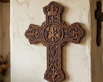 Puede incluir: Una cruz de pared de madera marrón con tallas intrincadas de vides, hojas y cruces pequeñas. El centro muestra un símbolo Chi Rho, mientras que la sección superior incluye una pancarta con el texto INRI grabado en la madera.
