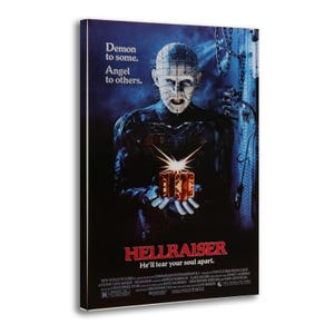 May include: A framed Hellraiser movie poster. The poster features a dark image of a character holding a puzzle box. Text on the poster reads "Demon to some. Angel to others." and "He'll tear your soul apart."