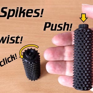 Op de afbeelding: Zwart, cilindrisch object met een getextureerd oppervlak van spikes. De afbeelding bevat de woorden "Spikes!", "Push!", "Twist!" en "click!" met een pijl die de actie aangeeft. Het object wordt in een hand gehouden.