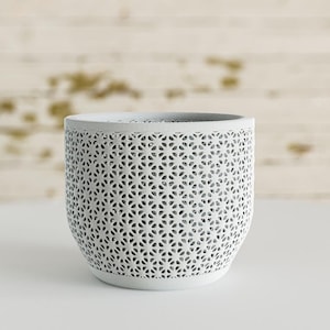 May include: A white ceramic mug with a black handle and the text "But First, Coffee" in a handwritten style. The mug is on a white surface. The mug is approximately 4 inches tall.