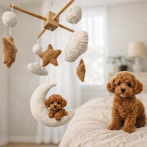 May include: A brown toy poodle sits on a bed next to a handmade baby mobile. The mobile features crocheted stars, clouds, moons, and spheres in shades of white and brown, suspended from a wooden frame. The nursery decor creates a cosy, whimsical atmosphere.