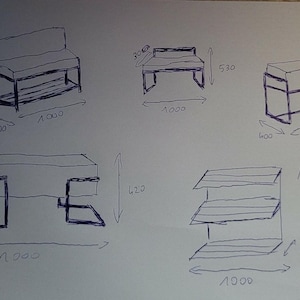 Op de afbeelding: Een wit vel papier met handgetekende schetsen in blauwe inkt van meubelontwerpen, waaronder banken en een plank met drie niveaus. Elke schets bevat handgeschreven metrische afmetingen in millimeters, zoals breedtes van 1000 mm.