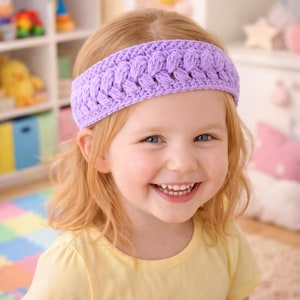 May include: A light purple, braided crochet headband. The headband is worn by a young child with blonde hair and a yellow shirt. The child is smiling at the camera.