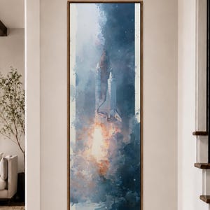 以下が含まれることがあります： 空に向かって打ち上げられるスペースシャトルの水彩画風イラストが描かれた、縦長の長方形のウォールアート。深い青、白、そして基部の鮮やかなオレンジ色の炎の色合いが特徴で、細い茶色のフレームに収められています。