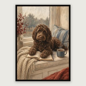 Puede incluir: Una impresión artística enmarcada que representa a un perro marrón de pelo rizado descansando en un asiento junto a la ventana. El perro tiene sus patas sobre un libro abierto junto a una taza azul de café humeante. Se ven una manta de punto crema, un cojín a rayas y un jarrón.