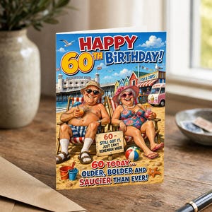 May include: A 60th birthday greeting card featuring a cartoon illustration of an older couple sitting in beach chairs on the sand. The text reads: HAPPY 60TH BIRTHDAY! 60- STILL GOT IT, JUST CAN'T REMEMBER WHERE. 60 TODAY... OLDER, BOLDER AND SAUCIER THAN EVER!