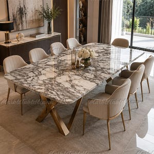 May include: A rectangular dining table with a white and grey marble top and a gold-toned metal X-shaped base, surrounded by eight upholstered chairs with vertical channel tufting and gold-toned metal legs, arranged in a dining room setting.
