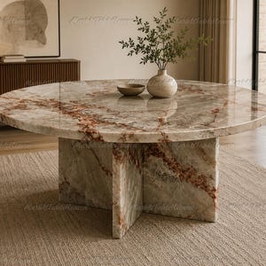May include: A round coffee table made of polished brown and white marble with prominent reddish-brown veining. The table features a thick circular top supported by a sturdy cross-shaped base made of the same matching marble material.