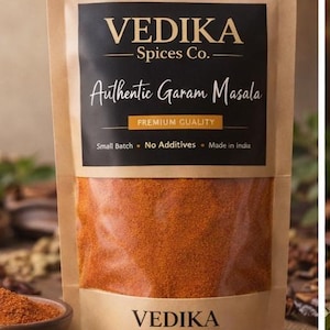 Può includere: Una busta verticale color marrone chiaro contenente una miscela di spezie Garam Masala color arancio-marrone. L'etichetta nera riporta il testo VEDIKA Spices Co. Authentic Garam Masala, Premium Quality, Small Batch, No Additives, Made in India.