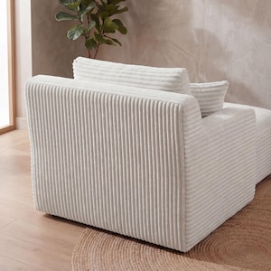 May include: A cream-colored corduroy armchair with a matching pillow. The chair has a ribbed texture and a rounded back. The chair is placed on a round, woven rug.