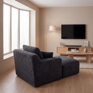 May include: A dark gray corduroy armchair with an attached ottoman sits in a modern living room. The room features a large window, a wooden coffee table, and a flat-screen TV mounted on the wall.