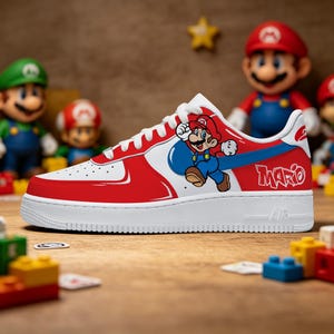 Puede incluir: Zapatilla Air Force 1 roja, blanca y azul con un gráfico de Mario. La zapatilla tiene una suela blanca y una parte superior roja y blanca con un logotipo azul. La palabra "Mario" está escrita en el lateral.