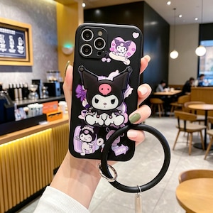 May include: Black phone case featuring a cartoon character with large ears, a pink nose, and a bow. The case has a black ring grip and a silver metal ring. The design includes purple and white accents.