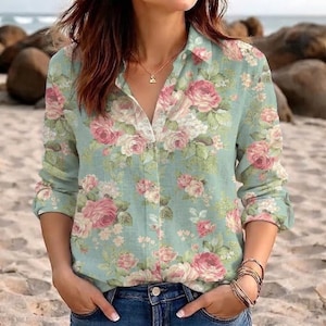Può includere: Una camicia a maniche lunghe con bottoni in color verde salvia chiaro con una stampa floreale di rose rosa e fiori bianchi. La camicia presenta un colletto classico, un'abbottonatura frontale ed è abbinata a un paio di jeans blu.