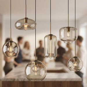Peut inclure: Ensemble de six lampes suspendues modernes avec des abat-jours en verre transparent teinté ambre. Chaque lampe est suspendue à un cordon noir et comporte une tige métallique dorée et une ampoule Edison visible. Les formes des abat-jours varient.