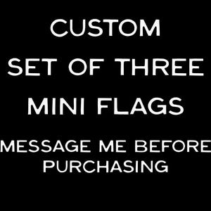 May include: A black graphic with white text that reads CUSTOM SET OF THREE MINI FLAGS followed by the instruction MESSAGE ME BEFORE PURCHASING. This text-based image serves as a clear announcement for a custom order of three small flags.