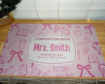 Könnte beinhalten: Rosa Schreibtischunterlage mit einem Design eines Kompositionsbuchs, mit dem Namen "Mrs. Smith". Die Unterlage enthält Illustrationen zum Thema Schule und den Text: "100 Blatt 200 Seiten 24,7 x 19,0 cm". Die Größe ist 9 3/4 x 7 1/2 Zoll.