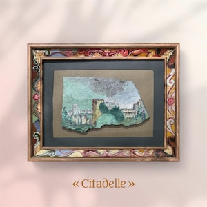 Può includere: Opera d'arte incorniciata con un dipinto ad acquerello di una scena di castello. Il dipinto è su una superficie strutturata, inserito in un passe-partout verde scuro e una cornice dorata decorativa. L'opera è intitolata "Citadelle".