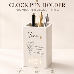 May include: A white rectangular wooden pen holder featuring a digital LED clock display at the base. The front is printed with the name Tina, a small heart, a floral illustration, and the text Perseverance leads to victory. Three pens are inside.