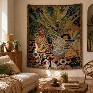 May include: A large tapestry featuring a tiger and a person reading a newspaper with the text "Le Monde". The tapestry has a jungle theme with green, yellow, and brown colors. The tapestry is hanging on a wall in a living room.