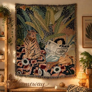 May include: A woven tapestry featuring a tiger and a person reading a newspaper with the text "Le Monde". The tapestry has a jungle theme with green, brown, and pink colors. The tapestry is fringed on the edges.