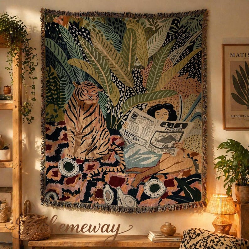 May include: A woven tapestry featuring a tiger and a person reading a newspaper with the text "Le Monde". The tapestry has a jungle theme with green, brown, and pink colors. The tapestry is fringed on the edges.
