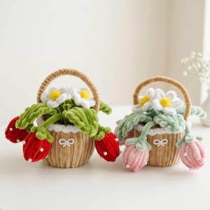 May include: Two small, round, tan corduroy baskets with handles, each containing plush flowers and berries. One basket features red berries with white beads, the other pink berries with white beads. Both have white daisy-like flowers and a small white bow.
