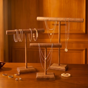 May include: Wooden jewellery display stands showcasing gold necklaces, bracelets, and rings. The stands have a T-shape design with a rectangular base. The jewellery includes delicate chains, a pendant necklace, and various bracelets.