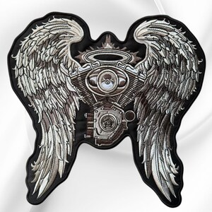 May include: An embroidered patch featuring a central motorcycle engine block topped with a halo, flanked by two large, detailed feathered wings. The design uses shades of grey, silver, and black thread on a black fabric background.