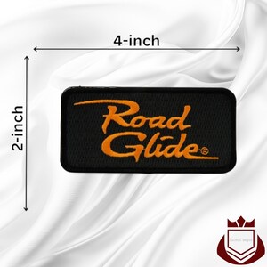May include: A rectangular black embroidered patch featuring the orange text Road Glide with a registered trademark symbol. The patch measures 4 inches in width and 2 inches in height as indicated by the black dimension lines on the image.