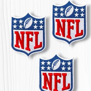 May include: Three embroidered NFL patches. Each patch is shield-shaped with a blue border, white stars, and a football graphic. The letters "NFL" are in red, centered within the shield.