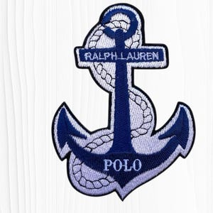 May include: Embroidered patch featuring a navy blue anchor design with white rope detailing. The patch includes the text "RALPH LAUREN" across the top and "POLO" at the bottom. The patch is likely for clothing or accessories.