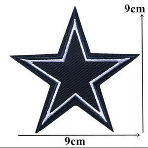 May include: A navy blue embroidered star patch, measuring 9 cm across. The star has a white outline and a smaller white star within. This patch is suitable for clothing or accessories.