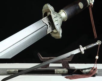 May include: A straight sword with a dark wood handle, a silver-toned metal guard featuring ornate detailing, and a double-edged steel blade with a visible folded pattern. A brown tassel hangs from the pommel, and a matching scabbard lies below.