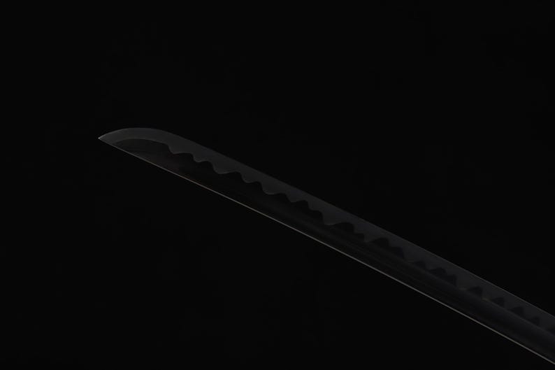 May include: A black katana blade with a curved edge and a serrated pattern along the spine. The blade is set against a black background, highlighting its sleek design and sharp details.