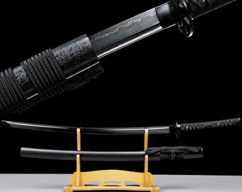 May include: A black katana sword with a curved blade, displayed on a wooden stand. The sword features a textured handle and a black scabbard. The blade has a visible pattern.