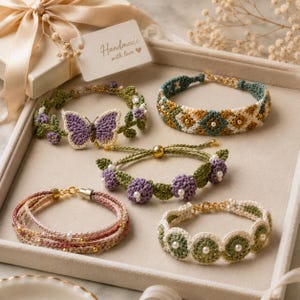 K&ouml;nnte beinhalten: Eine Sammlung handgefertigter H&auml;kelarmb&auml;nder in verschiedenen Designs. Ein Armband zeigt einen lila Schmetterling, andere florale Muster, geometrische Formen und Perlenakzente. Die Armb&auml;nder werden auf einem Tablett in neutralen T&ouml;nen pr&auml;sentiert. Ma&szlig;e in Zentimetern.