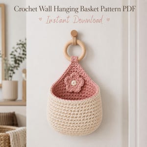 May include: A crocheted wall hanging basket in cream and pink, with a wooden ring and a flower applique. The text "Crochet Wall Hanging Basket Pattern PDF" and "Instant Download" is displayed at the top.
